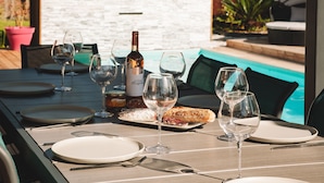 An outdoor dining area with a pool in the background.