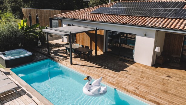 A swimming pool with a swan float, wooden deck, and a hot tub.