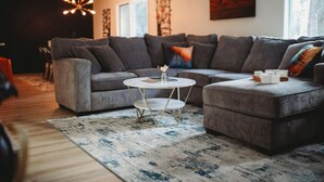 Ein modernes Wohnzimmer mit einer Eckcouch, einem runden Couchtisch und einem Teppich.