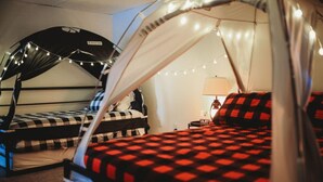 Ein Schlafsaalzimmer mit zwei Betten, jeweils mit Baldachin und Lichterketten.