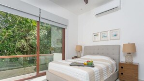 Ein Schlafzimmer mit einem großen Bett, zwei Nachttischen und einer Schiebetür, die auf einen Balkon führt.