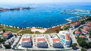 An aerial view of a coastal area with a marina, buildings, and a park.