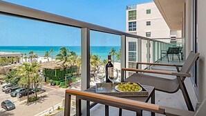A balcony with a table, a bottle of wine, and a plate of grapes. - Rooftop Pool| Ocean View Balcony|Hollywood Beach (Hollywood)