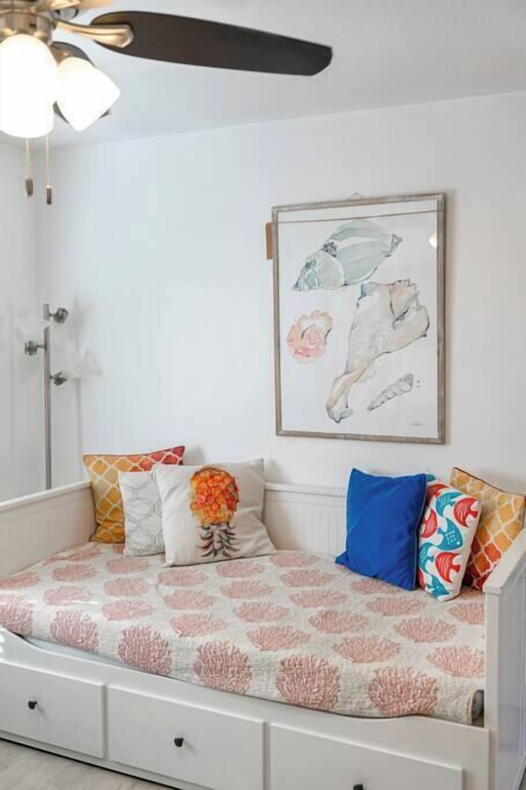 Une chambre à coucher avec un lit, un ventilateur de plafond, un tableau encadré et une douche.