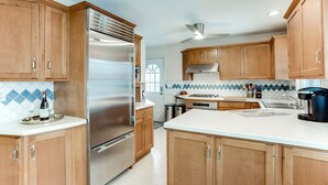 A modern kitchen with wooden cabinets, stainless steel appliances, and a tiled backsplash. - Charming Mid-Century Modern Eco-Friendly Home (Saint Paul)