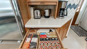A kitchen with a drawer containing various tea and coffee products. - Charming Mid-Century Modern Eco-Friendly Home (Saint Paul)