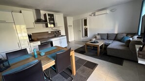A modern kitchen with white cabinets, a stove, and a dining area with a table and chairs. - Romantic vacation apartment with large pool and beautiful garden (Bale)