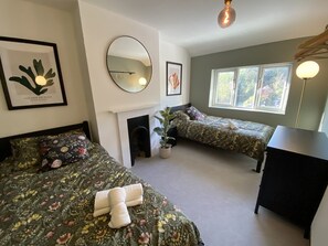 Ein Zimmer mit zwei Betten, einem Kamin, einem Spiegel und einem Fenster.