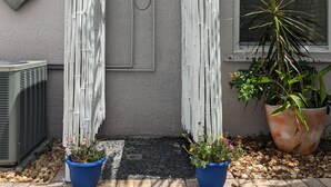 Una casa de fachada gris, una ventana con persianas y dos unidades de aire acondicionado.