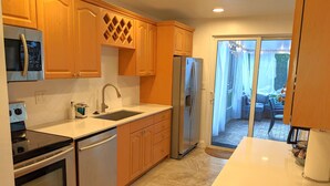 Una cocina moderna con electrodomésticos de acero inoxidable, armarios de madera y un ventanal que da a un patio.
