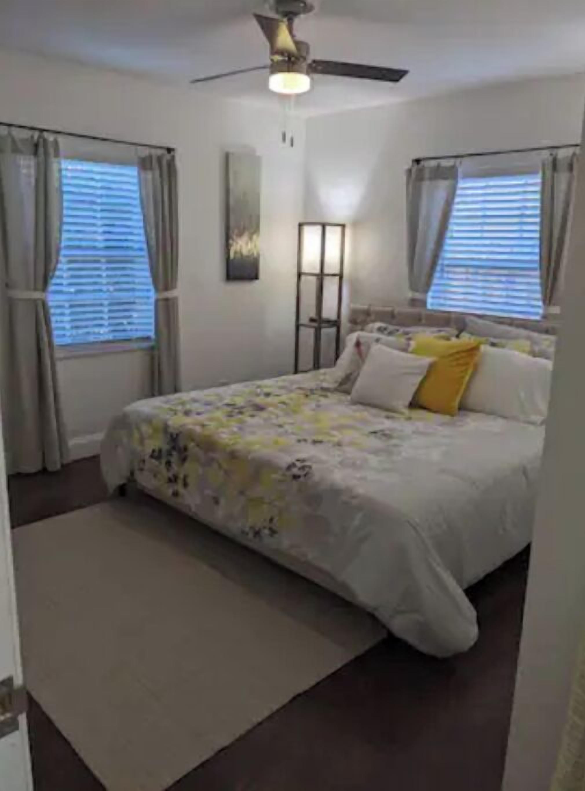 Ein Schlafzimmer mit Bett, Vorhängen, Deckenventilator und Stehlampe.