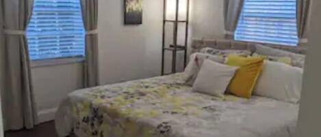 Ein Schlafzimmer mit Bett, Vorhängen, Deckenventilator und Stehlampe.