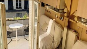 A compact room with a bed, a small table, and a television mounted on the wall. - Home Sweet Home Claridge Champs-Elysées (Paris)