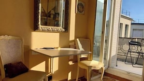A room with a checkered floor, a table, two chairs, a mirror, and a window with a view of buildings outside. - Home Sweet Home Claridge Champs-Elysées (Paris)