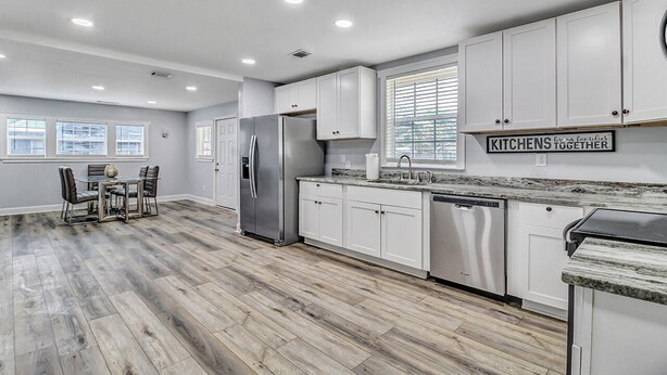 A modern kitchen with white cabinets, a stainless steel refrigerator, and a granite countertop. - 5 minutes drive to downtown Savannah. (Savannah)