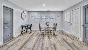 A dining area with a glass table and chairs, a clock on the wall, and a window with blinds. - 5 minutes drive to downtown Savannah. (Savannah)