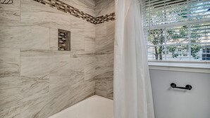 A bathroom with a bathtub, a window with blinds, and a shower area with a tiled wall. - 5 minutes drive to downtown Savannah. (Savannah)