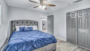 A bedroom with a tufted headboard, a blue bedspread, a ceiling fan, and a wooden floor. - 5 minutes drive to downtown Savannah. (Savannah)