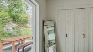 A bedroom with a bed, a large mirror, and a wooden bench outside the door.