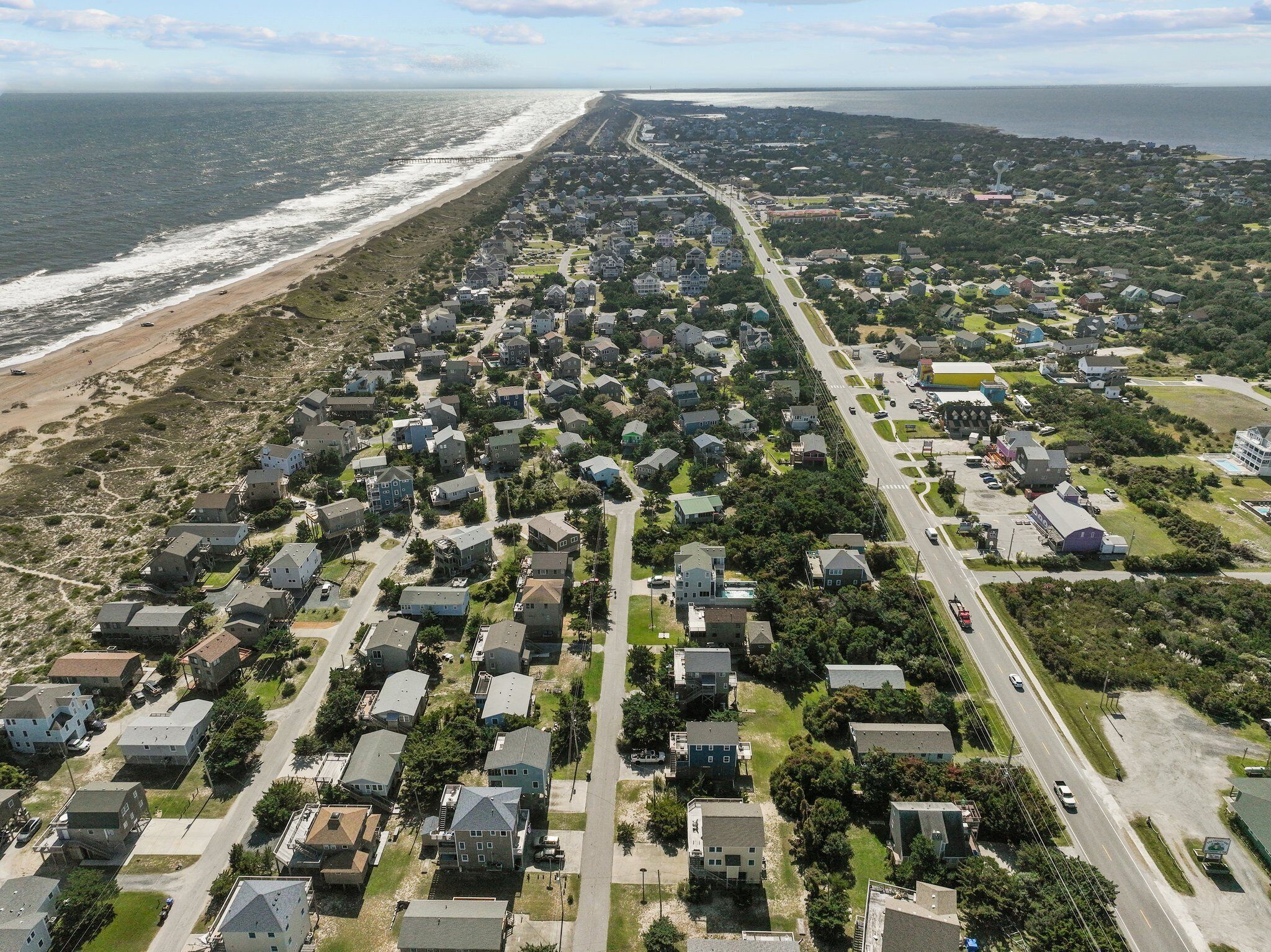 Vista aérea de una zona residencial costera con casas, caminos y una playa.