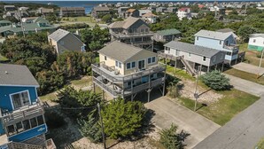 A coastal residential area with multiple two-story houses, some with balconies, and a view of the ocean in the background.