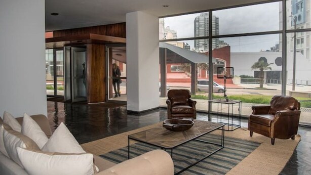 Eine moderne Lobby mit Glaswand, Ledersesseln, einem Couchtisch und einer Couch.