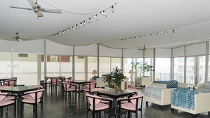 Ein großzügiger Innenbereich mit Tischen, Stühlen und einer Couch, ausgestattet mit Deckenventilatoren.