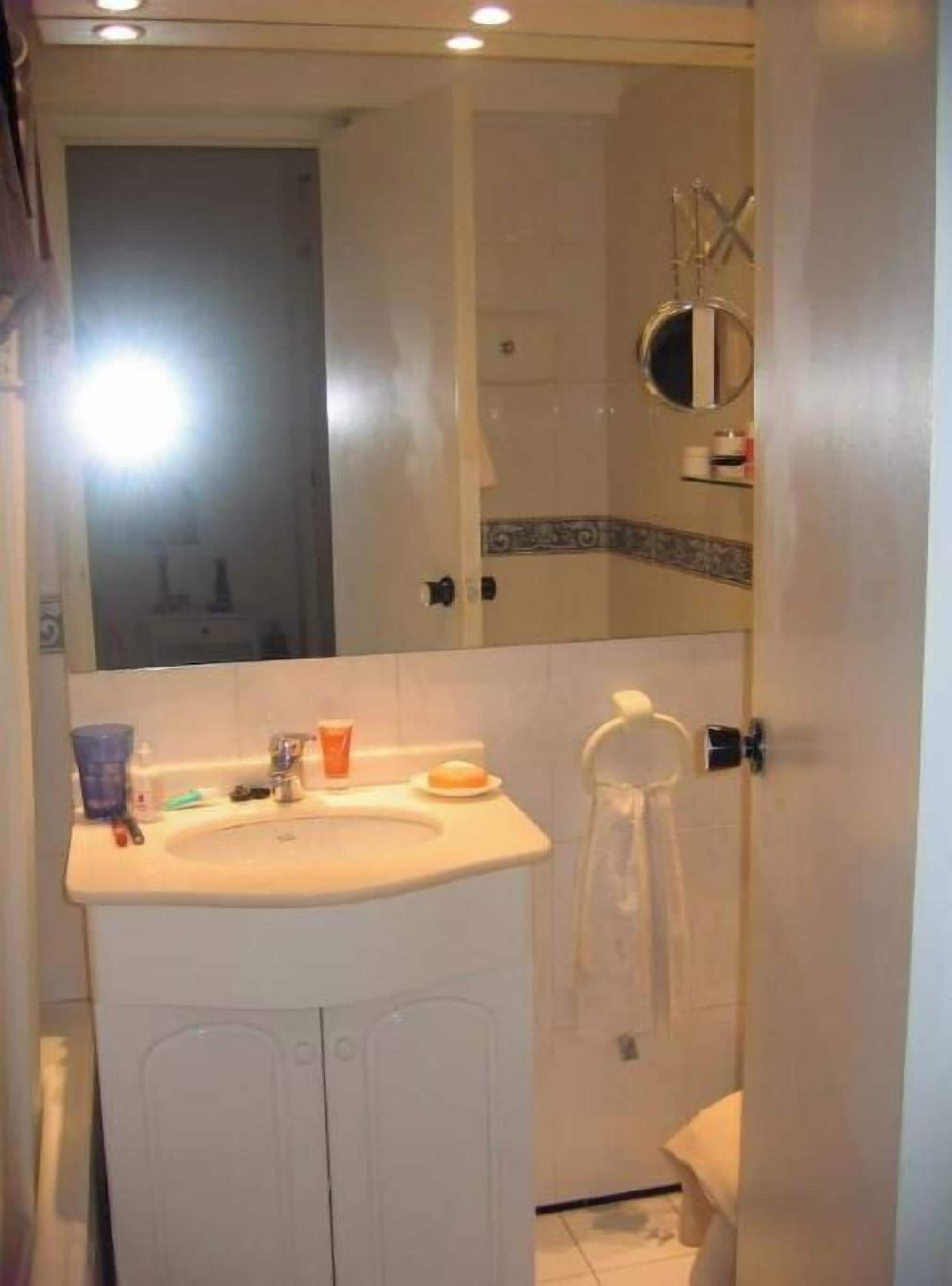 A bathroom with a sink, mirror, and towel rack.