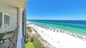 A balcony with a view of a beach with white sand and clear blue water, a pier, and several umbrellas. - ☀️Gulf Front, Amazing Views-Long Beach Resort 1-1203☀️ (Panama City Beach)