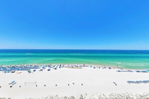 Ein Strand mit Reihen blauer und wei ßer Strandstühle, weißem Sand und dem Meer im Hintergrund.