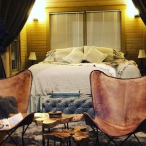 A bedroom with a large bed, two bedside lamps, and a window with blinds. - Beardsicle Bluff Cabin (Chatsworth)