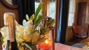 Une table en bois, avec une bouteille de vin, une lanterne et un arrangement floral.