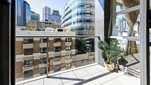A modern building with a glass facade and a balcony with potted plants. - A Stylish Apt for 6 Right Next to Darling Harbour (Sydney)