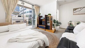 A modern hotel room with a large bed, a sofa, a TV stand, and a view of the city. - A Stylish Apt for 6 Right Next to Darling Harbour (Sydney)