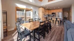 Una cocina amplia con electrodomésticos modernos, un comedor con mesa y sillas de madera, y un dormitorio en entrepiso con balcón.