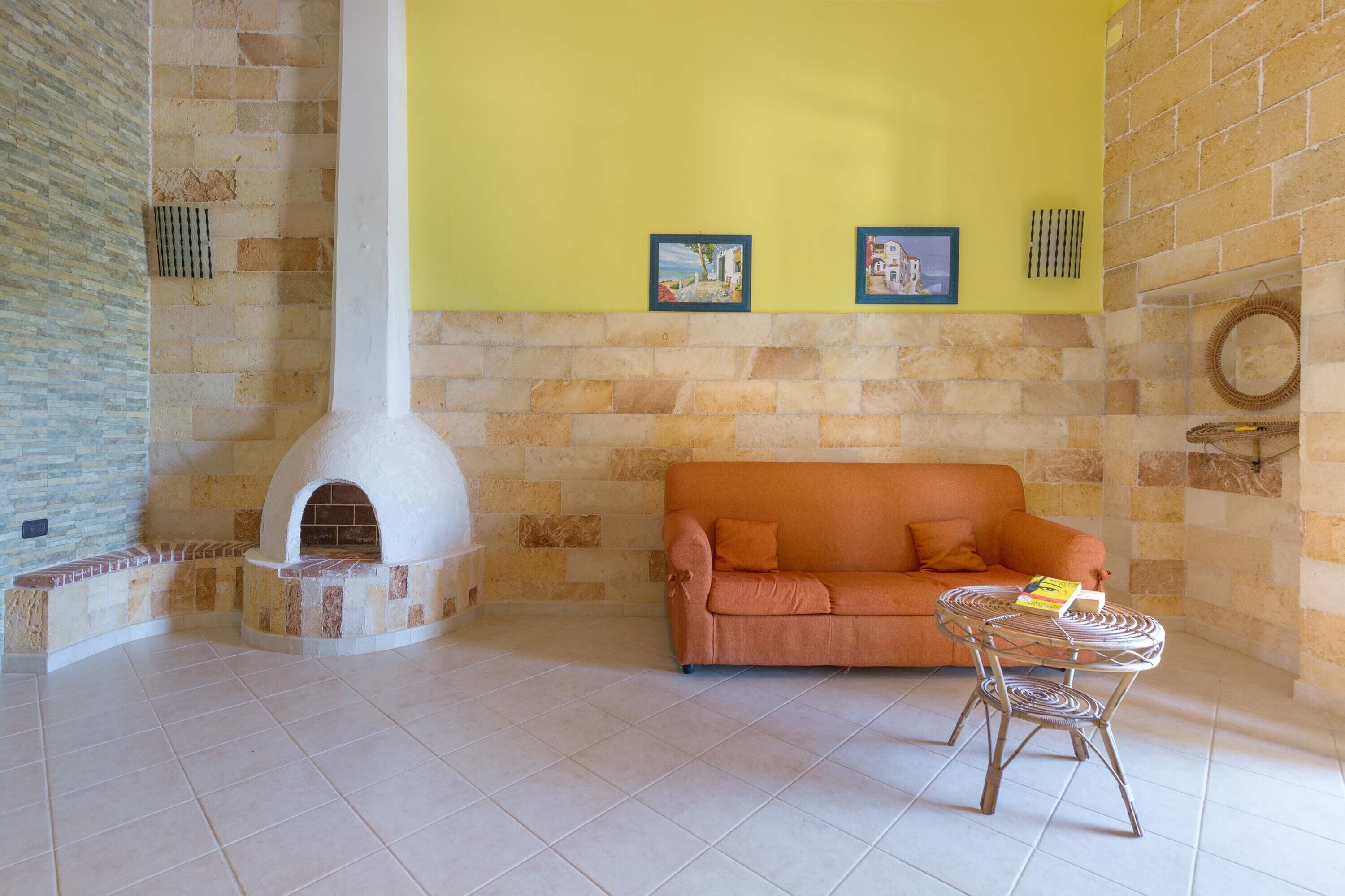 A room with a stone fireplace, a yellow wall, a sofa, and a small table.
