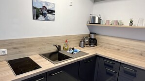Eine moderne Küche mit schwarzem Arbeitsplatz, Edelstahlgeräten und einer Holzrückwand.