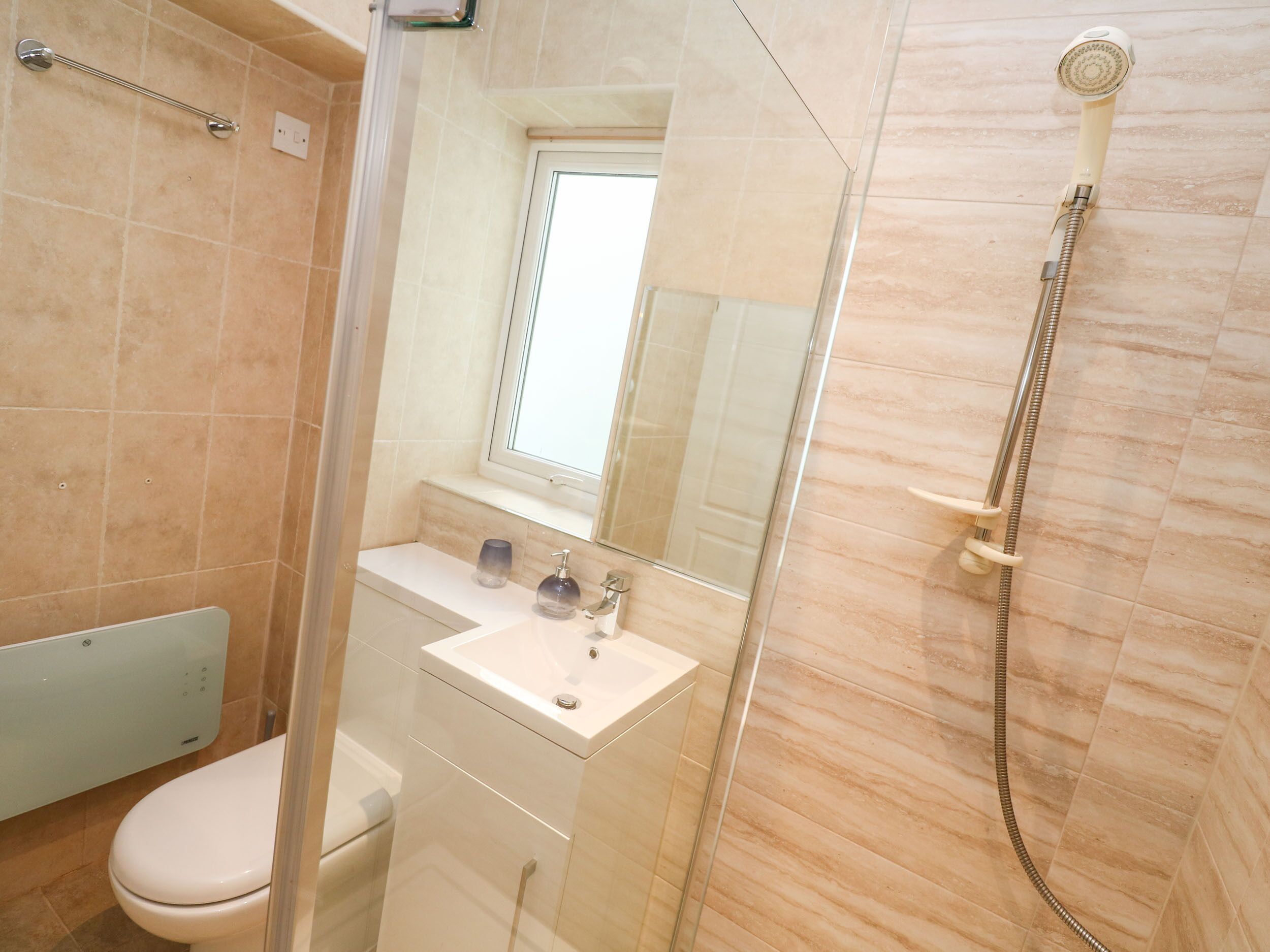 A modern bathroom with a glass shower enclosure, a white sink, and a toilet.