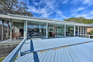 A modern building with a glass facade, wooden deck, and outdoor seating area. - 'Brookside' Waterfront Home w/ Kayaks & Deck! (Jacksonville)