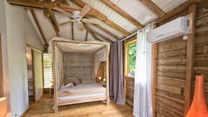 Ein hölzernes Himmelbett mit Baldachin, Deckenventilator und Klimaanlage.
