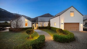 Una moderna casa a due piani con vialetto, giardino anteriore e garage.