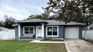 A single-story house with a front porch, a garage, and a well-maintained lawn. - Riverside Riviera at Seminole Heights (Tampa)