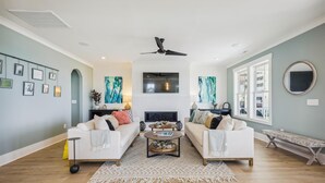 A living room with a fireplace, two sofas, a coffee table, and artwork on the walls. - Atlantic Oasis - Oceanview - Pool & Hot Tub - 6 Bed (North Myrtle Beach)