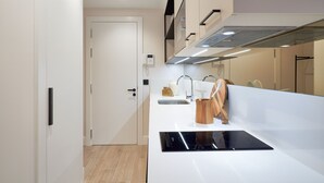 A modern kitchen with a black induction cooktop, a white countertop, and a stainless steel sink. - iloftmalaga Muelle Uno VI (Málaga)