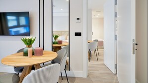 A modern dining area with a wooden table, chairs, and a TV mounted on the wall. - iloftmalaga Muelle Uno VI (Málaga)
