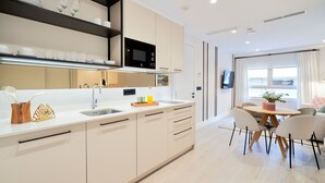 Una cocina moderna con una isla central, microondas integrado y un comedor con una mesa redonda y sillas.