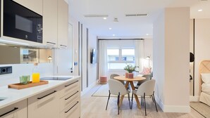 Una cocina moderna con microondas integrado, un comedor con una mesa redonda y sillas, y un ventanal que proporciona luz natural.