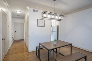 Una cocina moderna con refrigerador integrado, una mesa de comedor de madera con bancos, y una lámpara colgante arriba.