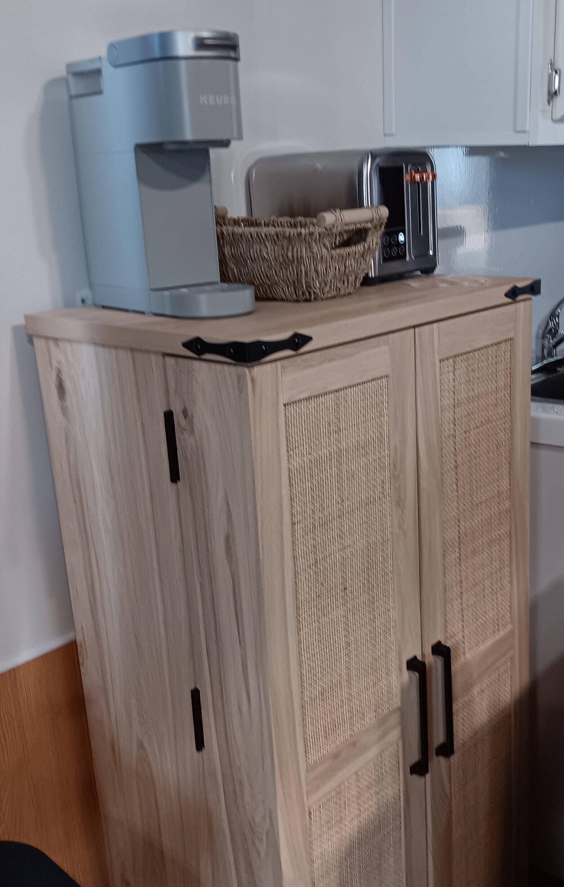 A wooden cabinet with a coffee maker and toaster on top.