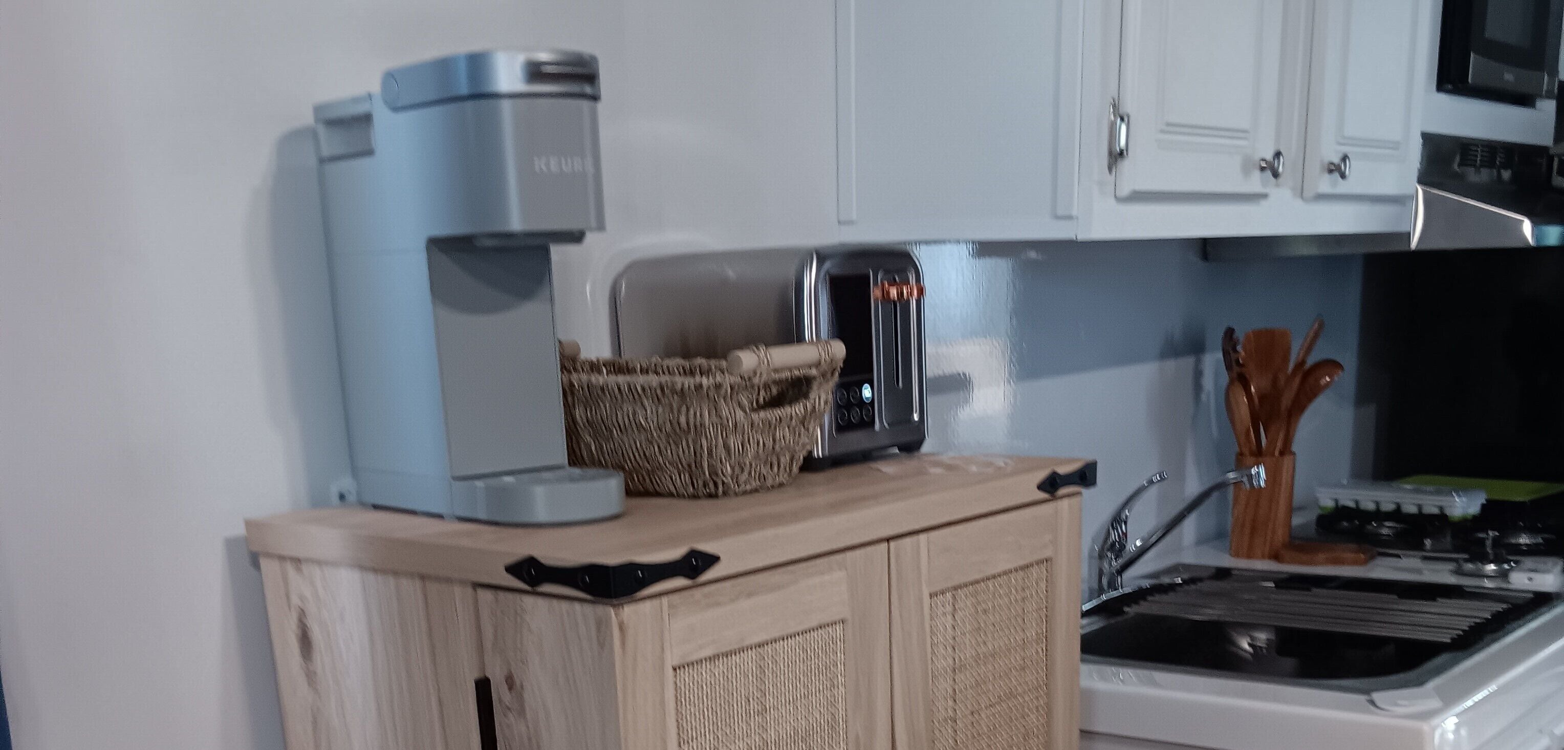 Une cuisine équipée d’une machine à café, d’un grille-pain et d’un panier posé sur le plan de travail.
